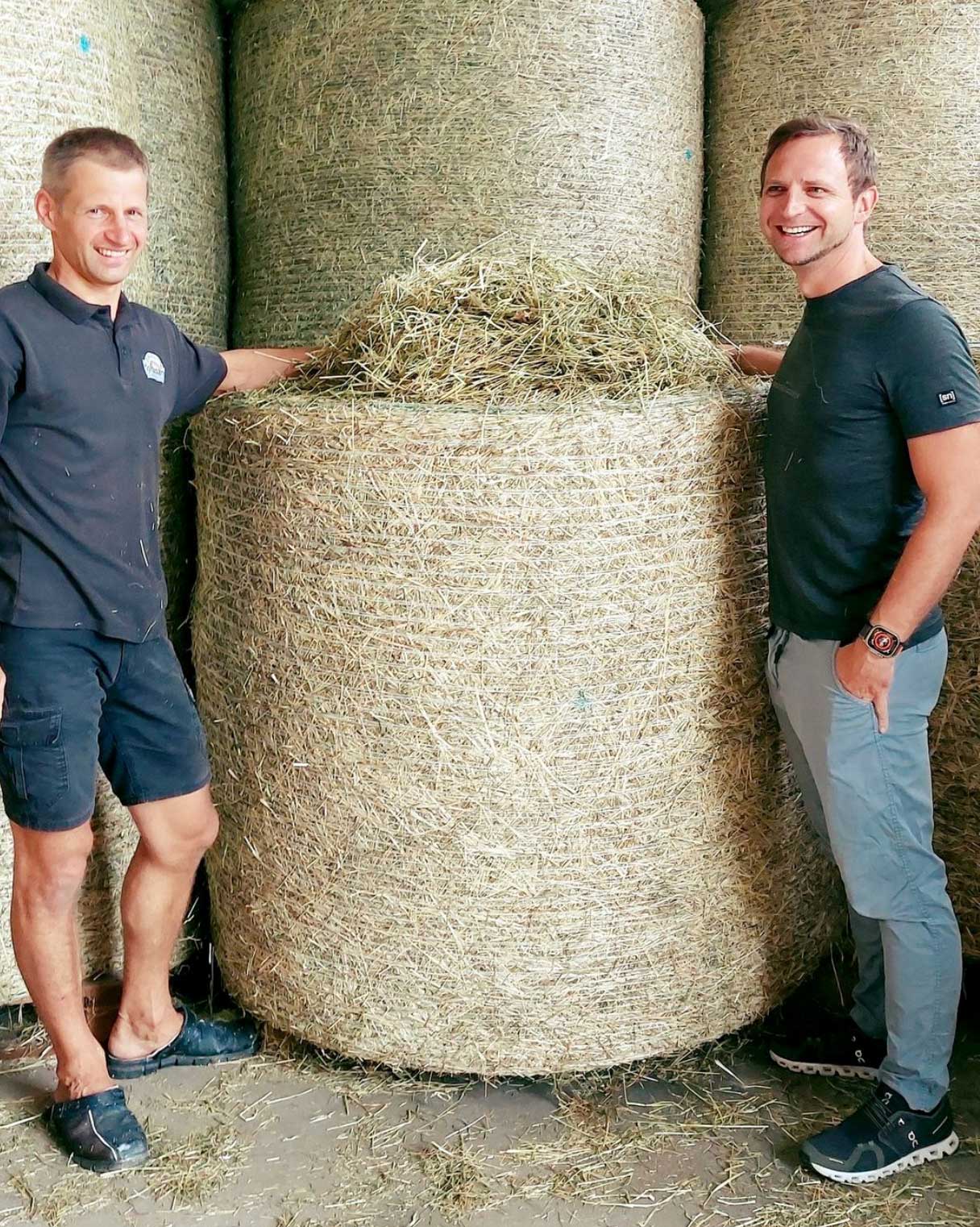 Partnerlandwirt und Florian Gollob stehen neben großen Ballen hochwertigem Pferdeheu.